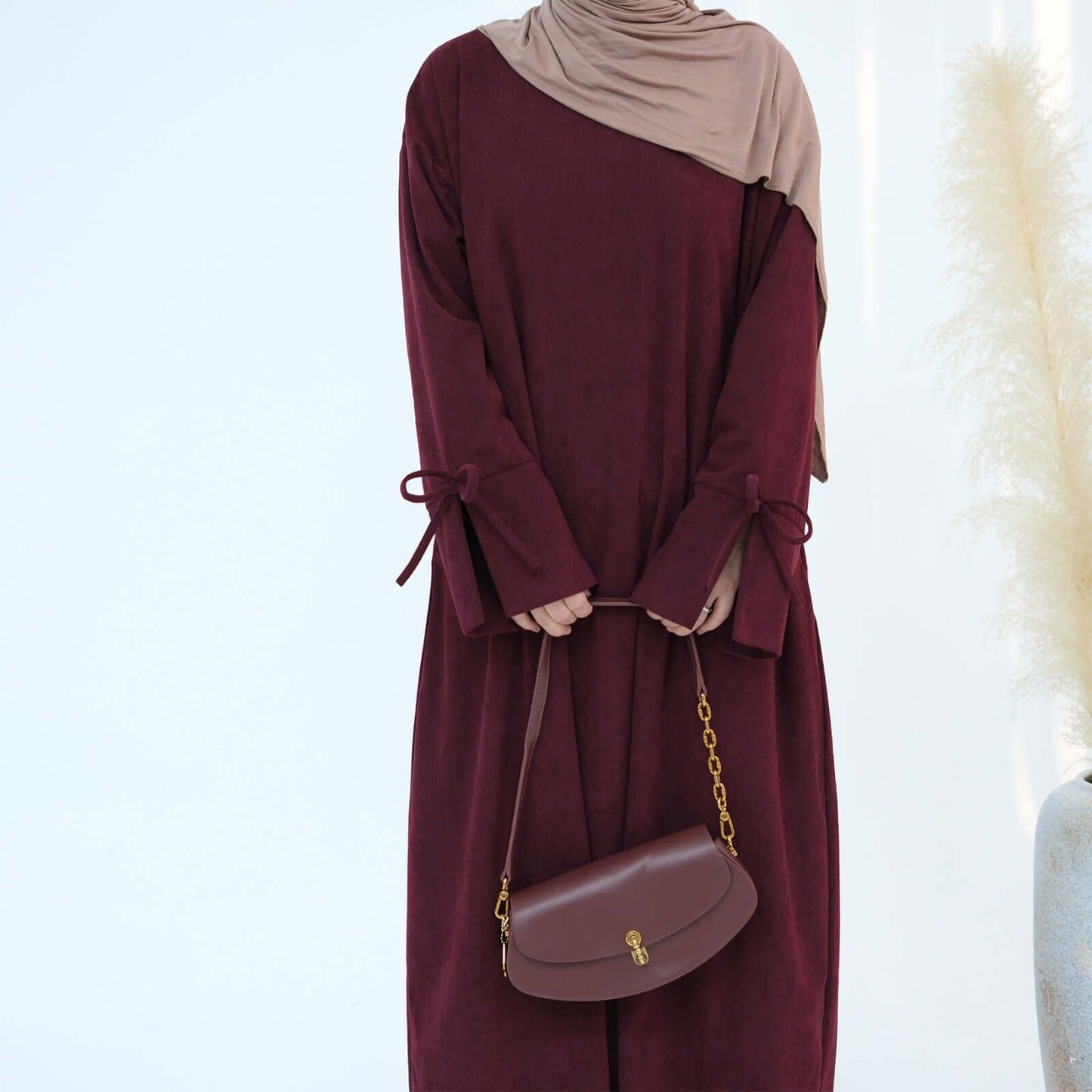 Nawal Corduroy Abaya in burgundy, featuring tie details at sleeves and elegant design for modest styling.