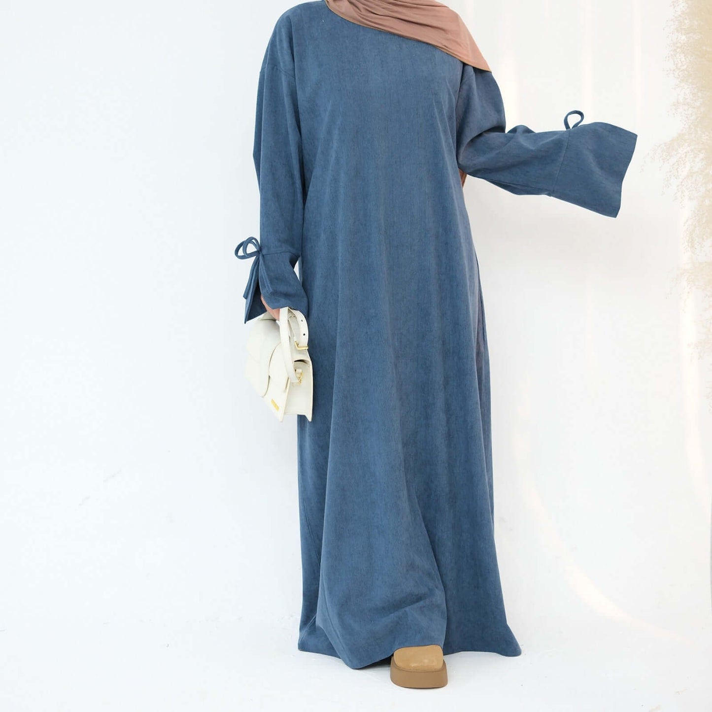 Nawal Corduroy Abaya in soft blue, featuring adjustable tie sleeves and a modern design for everyday elegance.